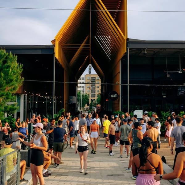 A large crowd of people gathered outside Highline Park, a modern building with a distinctive yellow entrance.
