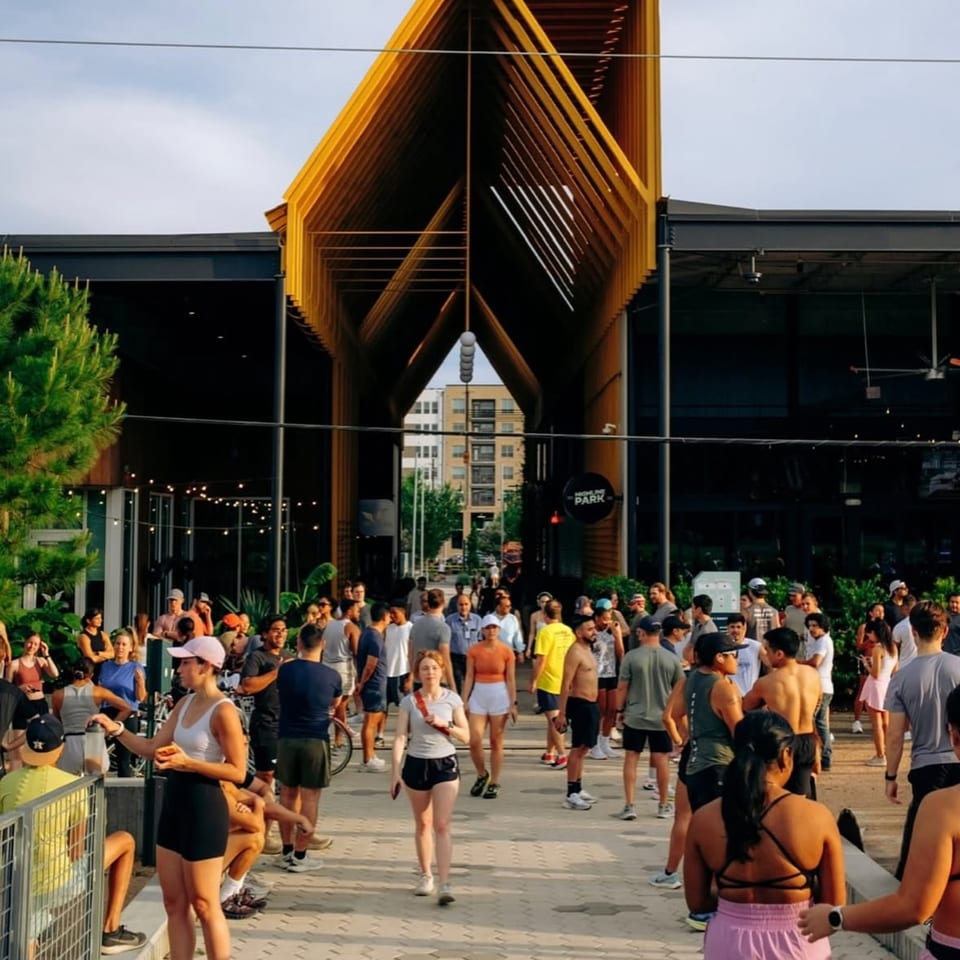 A large crowd of people gathered outside Highline Park, a modern building with a distinctive yellow entrance.