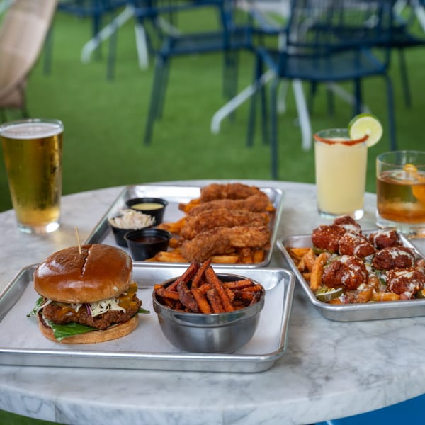 Highline Park's bar-and-grill spread: chicken sandwich, sweet potato fries, tenders, loaded fries, and drinks.