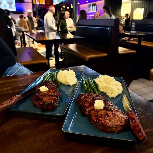Two steak dinners with mashed potatoes and green beans on blue plates at Highline Park.