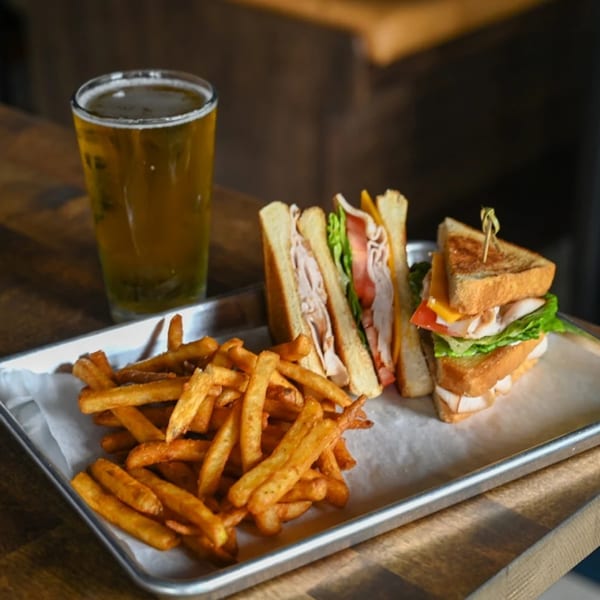 Highline Park's turkey club sandwich with fries and a beer on a metal tray.