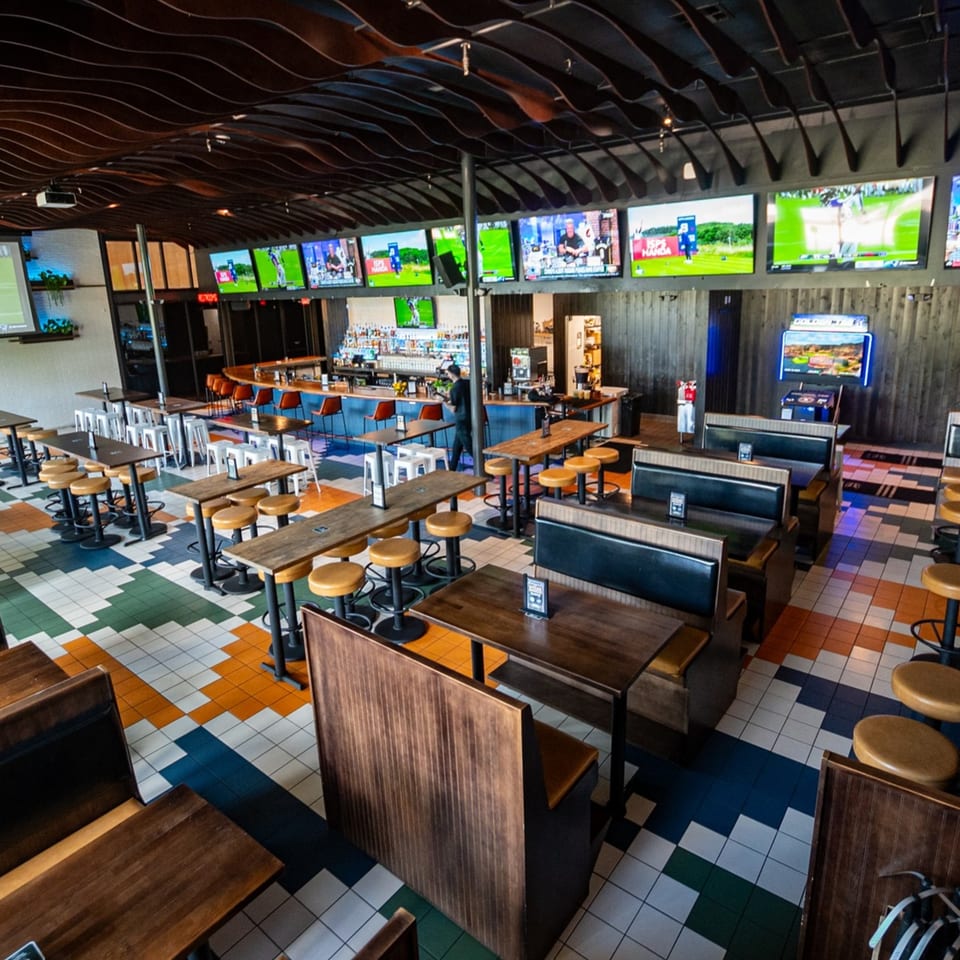 Highline Park bar-&-grill interior with multiple TVs, a long bar, and various seating arrangements.